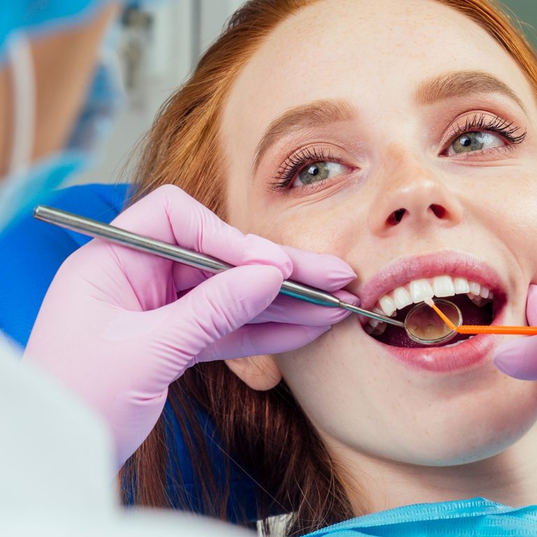 Portrait of an attractive smiling redhaired ginger customer girl in a dental chair in dental cabinet.She is not fear .